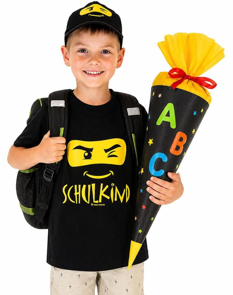 Junge mit Schulkind T Shirt und Basecap hält Zuckertüte und trägt Schulranzen zur Einschulung.