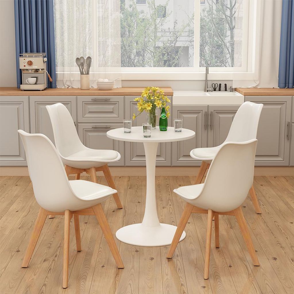 A dining set with a round white table and four white chairs in a kitchen setting.