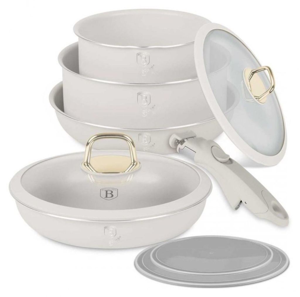 A set of white cookware with gold accents, including pots, a pan, a detachable handle, and lids, arranged on a white background.