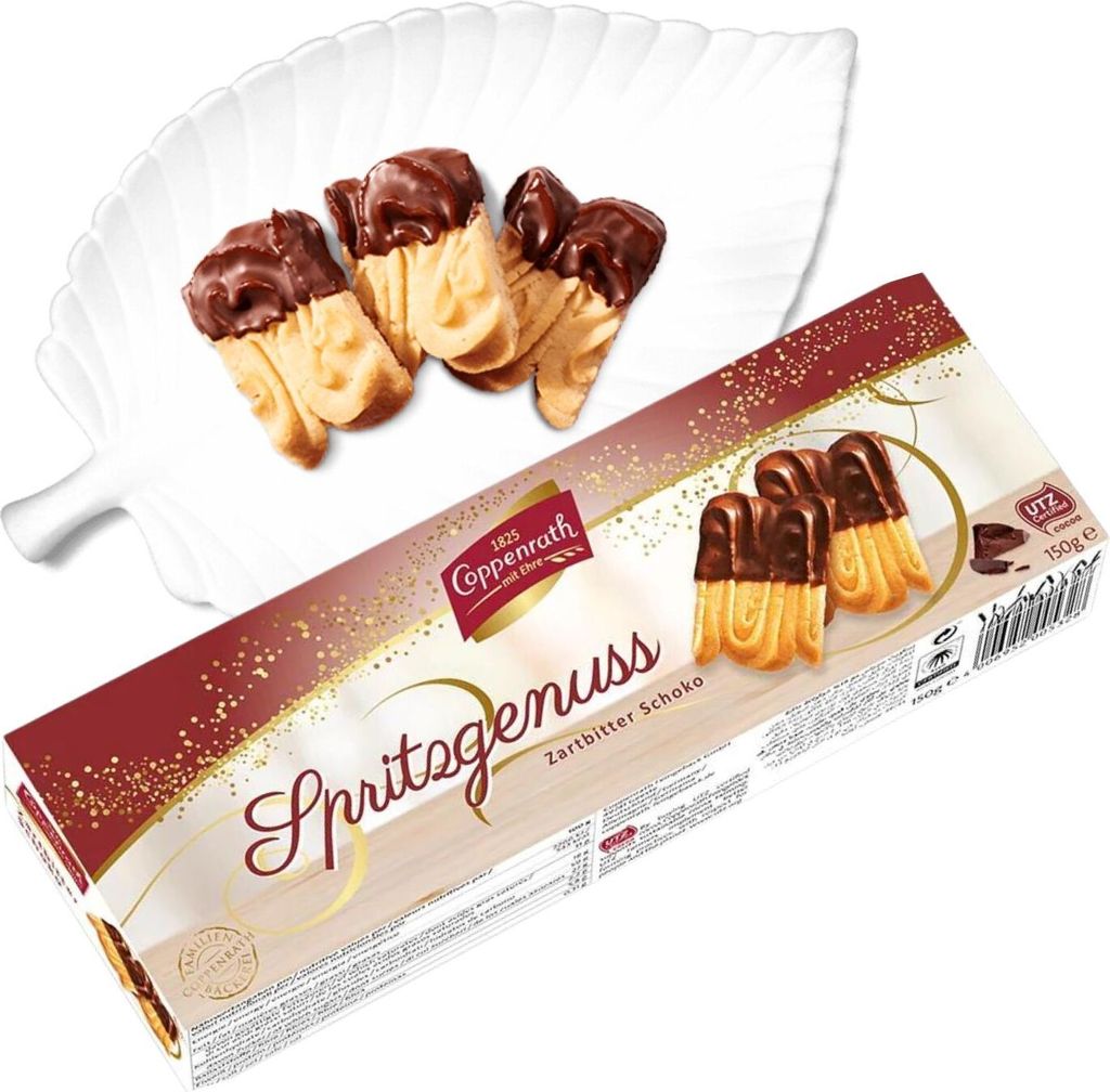 A box of Coppenrath Spritzgenuss Zartbitter Schoko cookies with some cookies displayed on a white leaf-shaped plate.