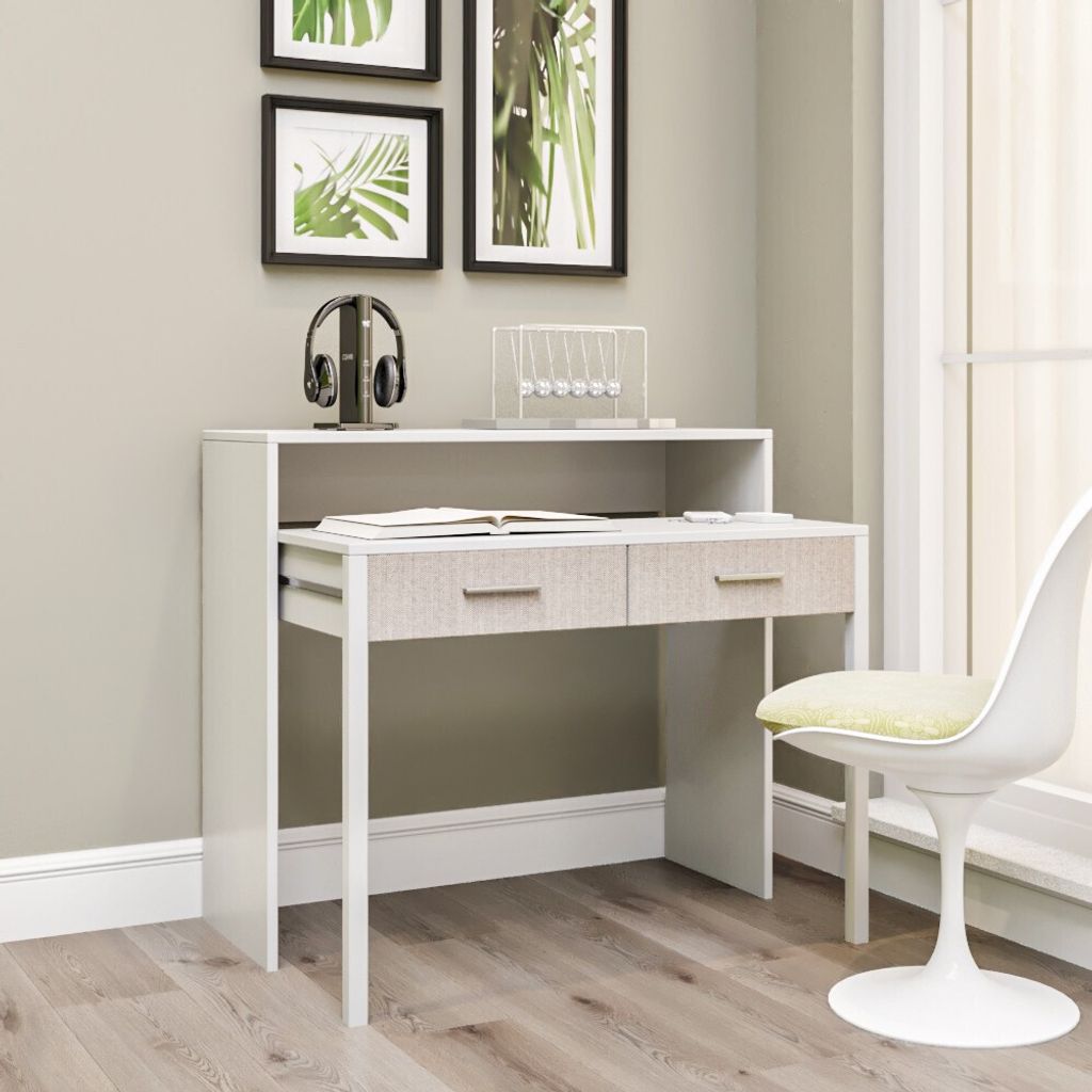 A desk with drawers and a shelf, placed in a room with artwork on the wall and a chair nearby.