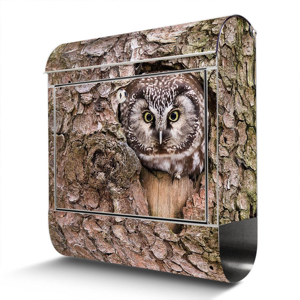 A mailbox designed to look like a tree trunk with an owl peeking out of a hole.