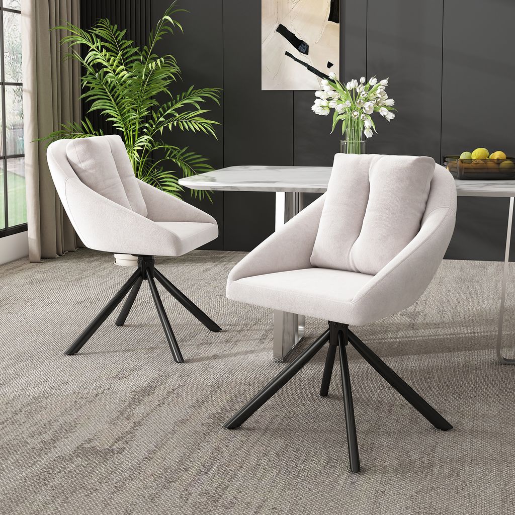 Two beige upholstered chairs with black metal legs are placed in a dining room setting.