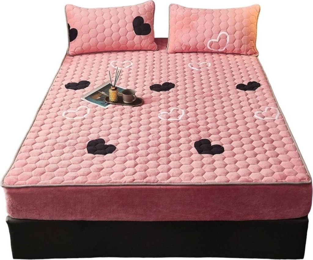 Rosa gesteppte Matratzenauflage mit schwarz-weißen Herzmustern, auf einem Bett mit zwei passenden Kissen