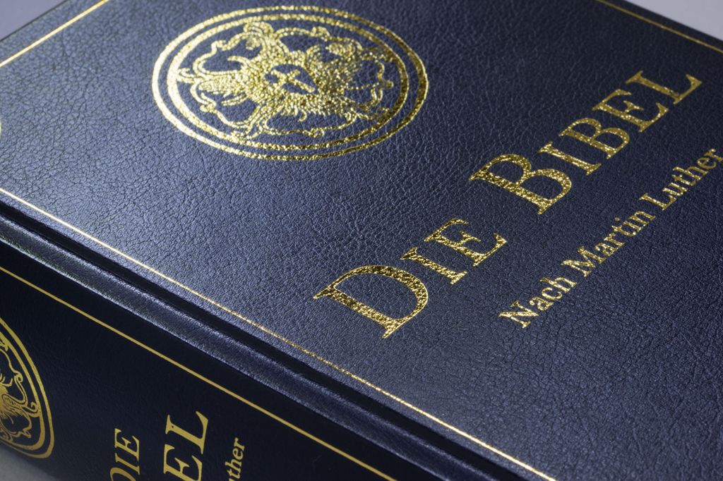 A close-up of the cover of a dark blue Bible with gold lettering and a gold emblem.