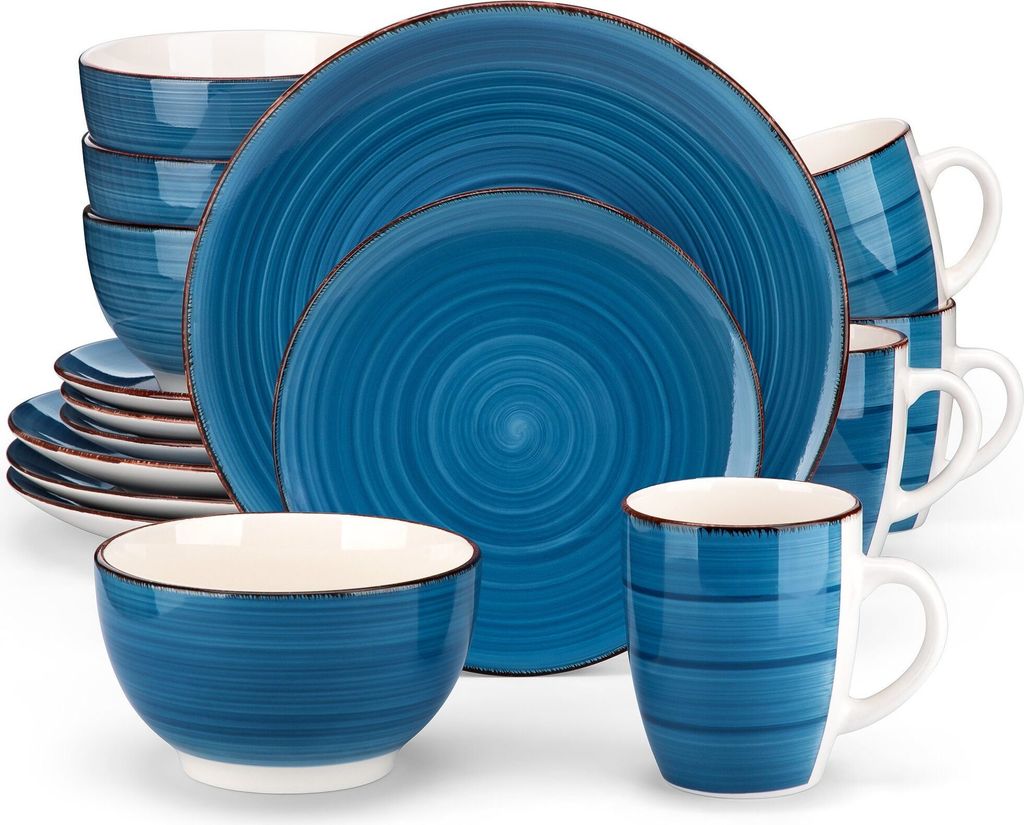 A set of blue ceramic dishes, including plates, bowls, and mugs, arranged in a studio setting.