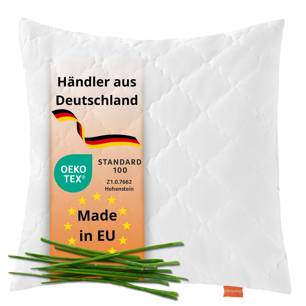 A white quilted pillow with a label showing product information and a small bunch of chives in the foreground.