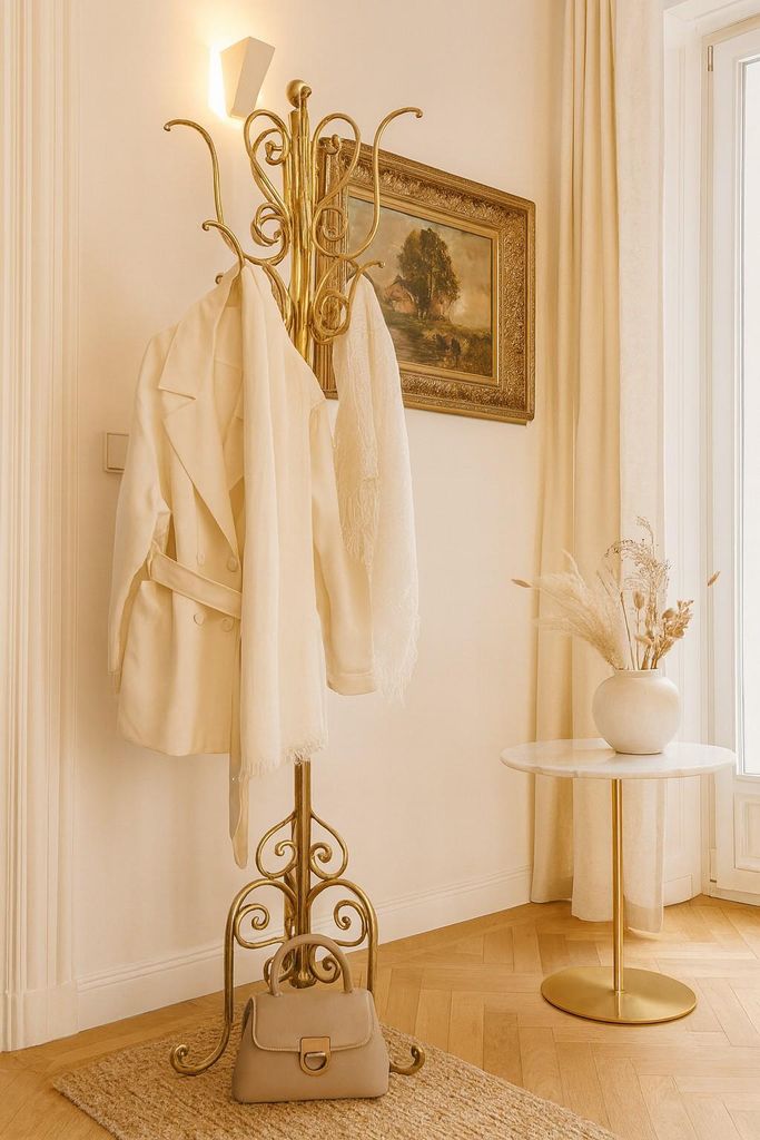 A hallway with a coat rack, painting, and side table.