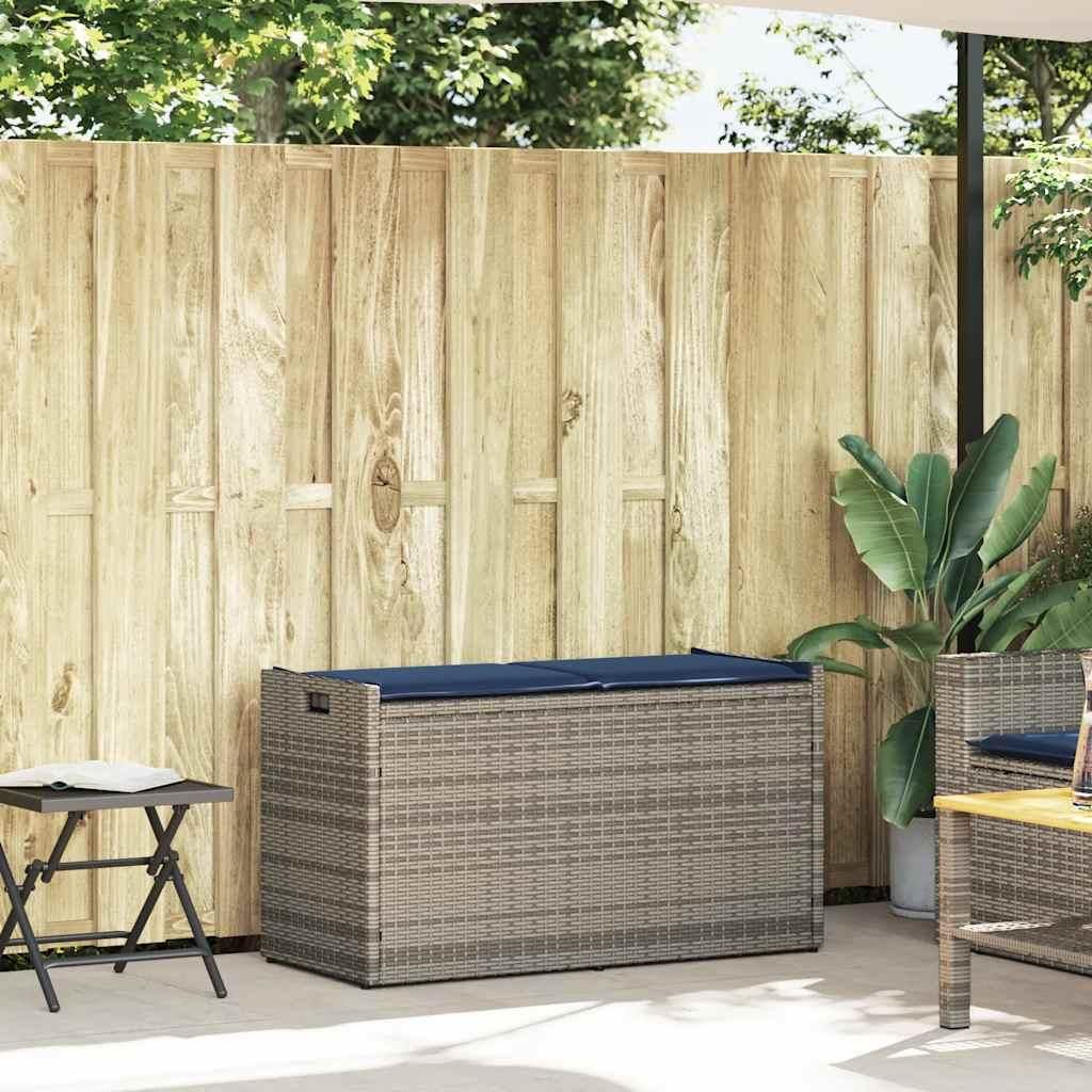 An outdoor storage bench with a cushion sits on a patio next to a wooden fence and a small folding table.
