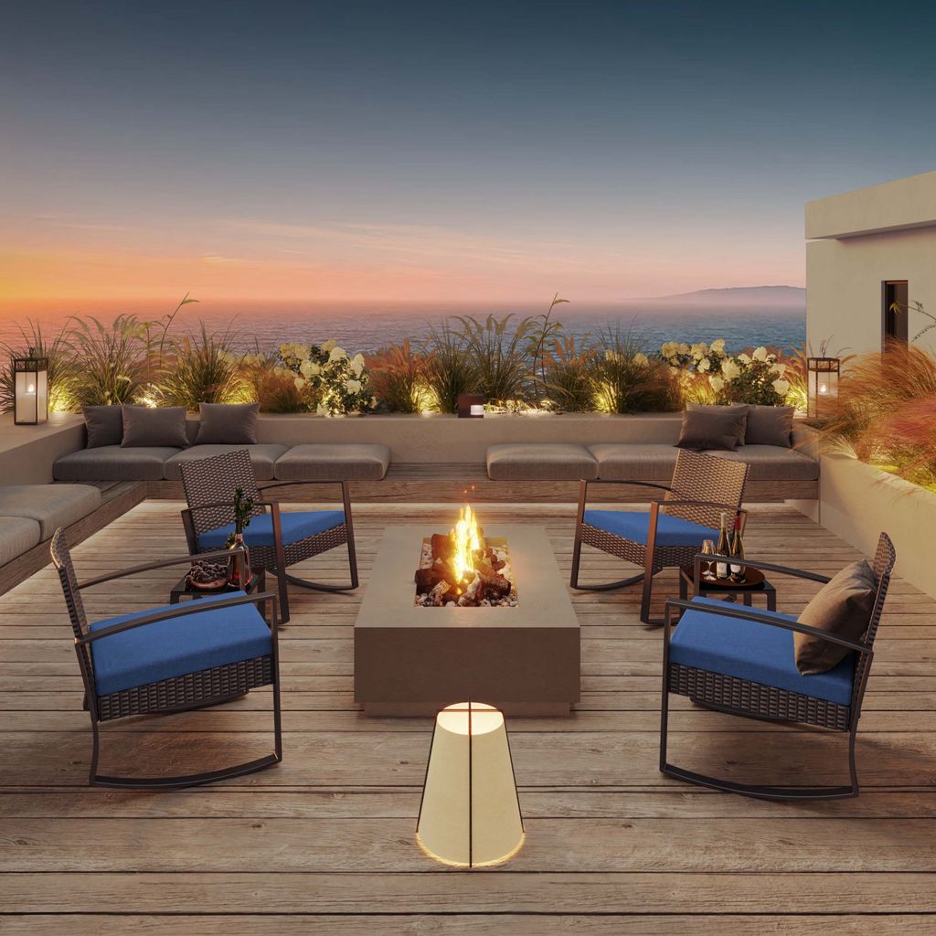 A rooftop patio with a fire pit and seating area overlooking the ocean at sunset.