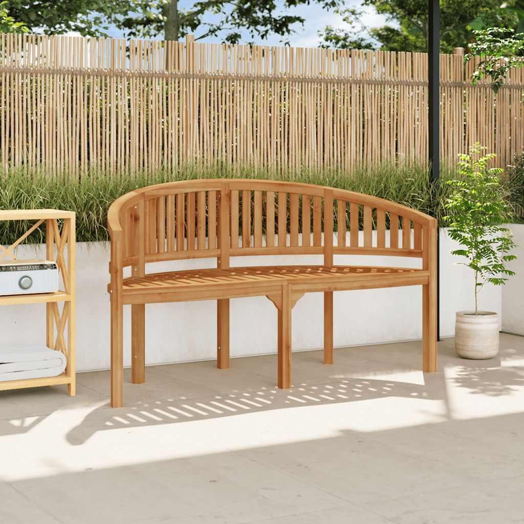A wooden bench sits on a patio in front of a bamboo fence.