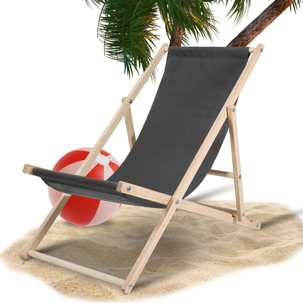 A beach chair and beach ball on sand with a palm tree overhead.