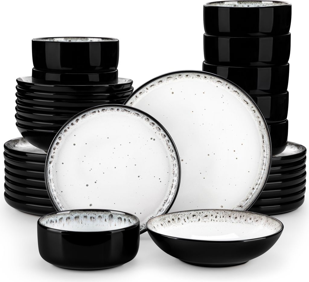 A collection of black and white speckled ceramic plates and bowls stacked and arranged on a white background.