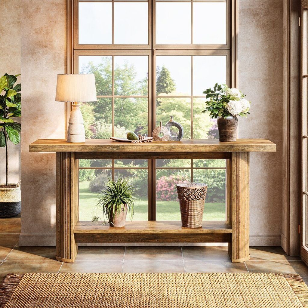A console table with decorative items placed on it, set against a large window with a garden view.