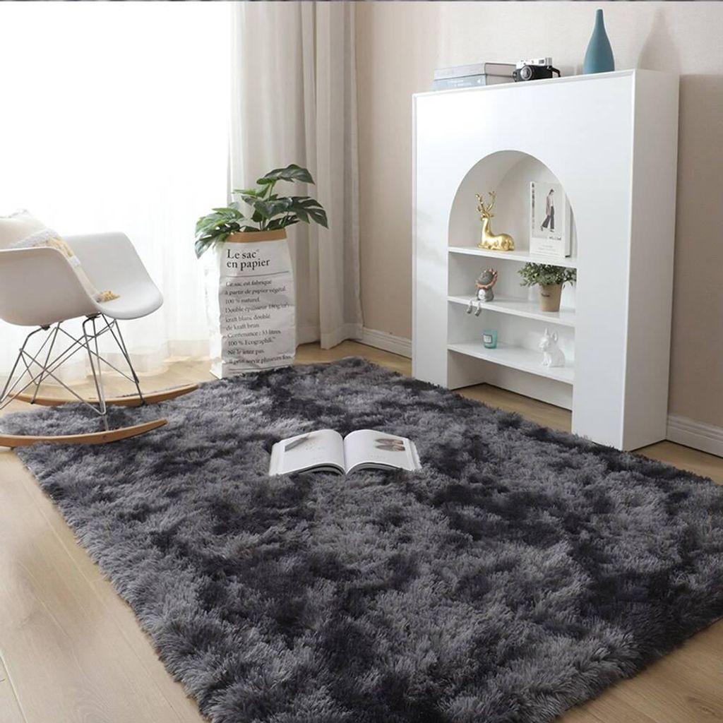 A cozy living room scene with a shaggy rug, rocking chair, and bookshelf.