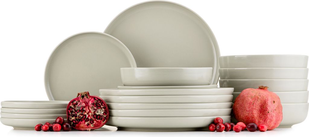 A set of beige ceramic dishes with pomegranates and cranberries.