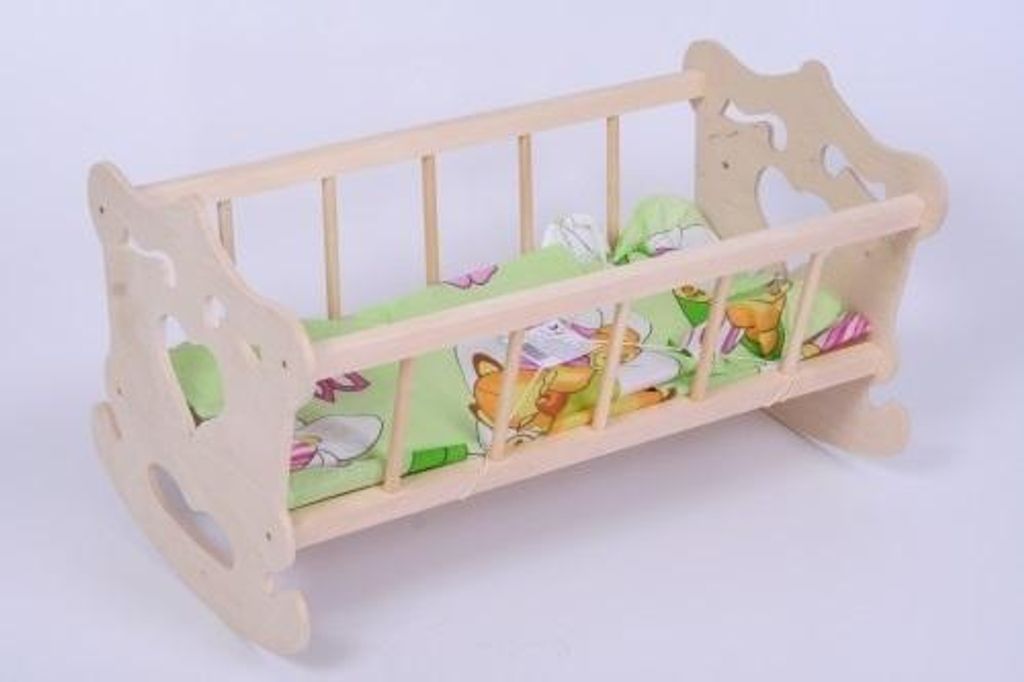 A wooden rocking cradle for a doll, with green bedding featuring cartoon animals.