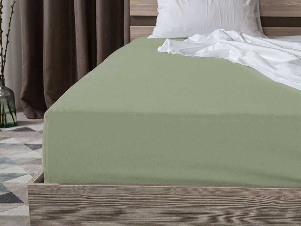 A close-up view of a light green fitted sheet on a bed.