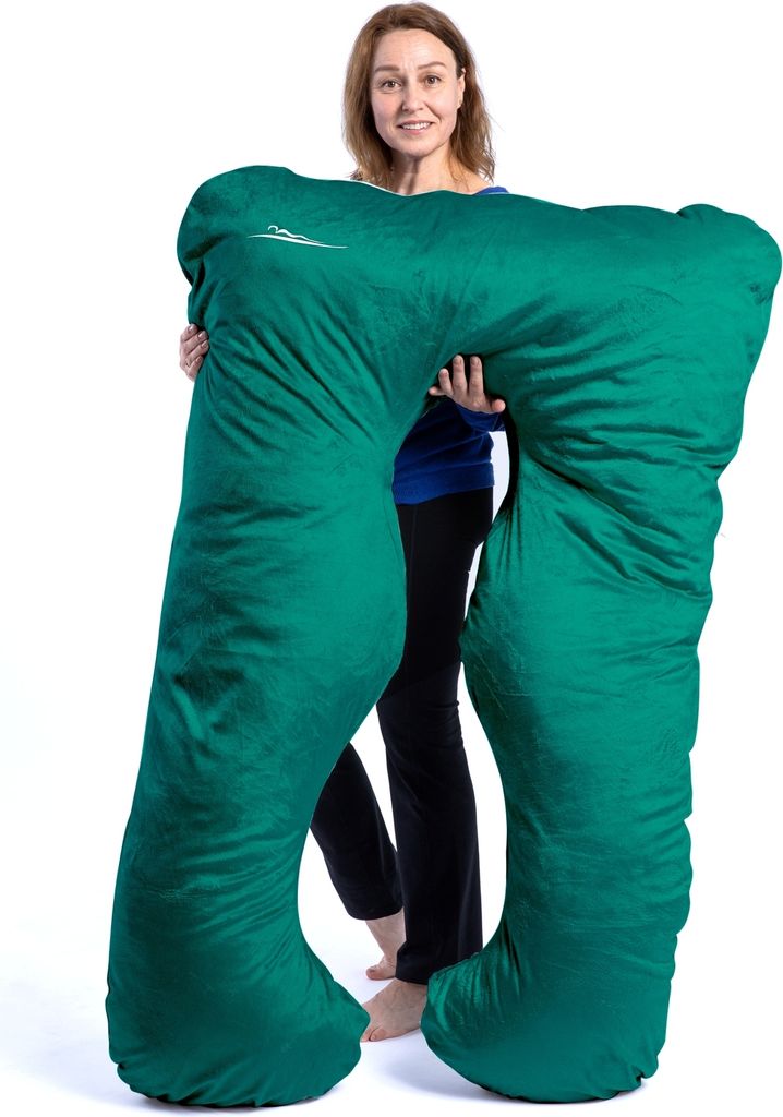 A woman is holding a large green pillow.