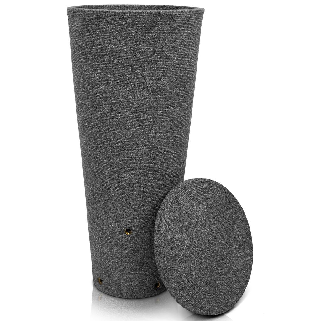 A tall, tapered, dark gray rain barrel with a textured surface and a separate round lid resting next to it. The barrel has small holes near the bottom.