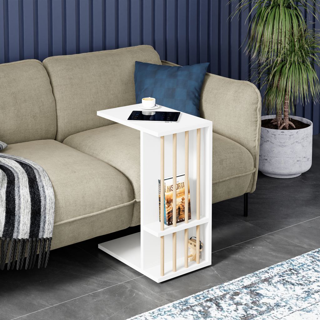 A white side table with books and a cup of coffee is placed next to a beige sofa in a living room setting.