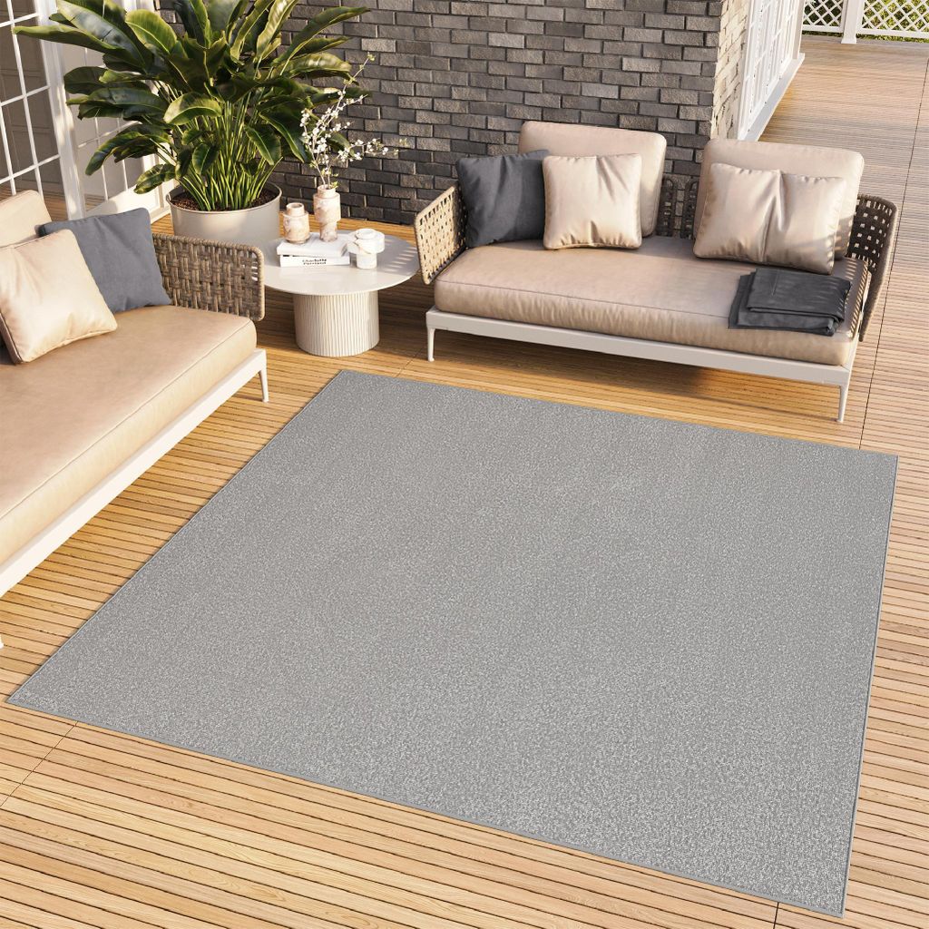 An outdoor patio setting with furniture and a rug.