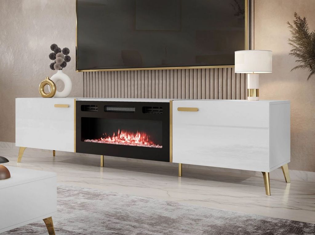 A modern white TV stand with a built-in electric fireplace, illuminated by a lamp and decorative vase.