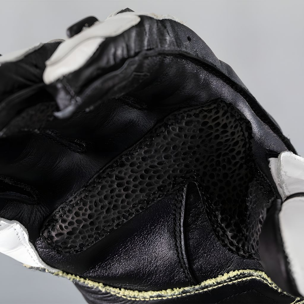 A close-up view of a black and white motorcycle glove, focusing on the textured material and stitching.