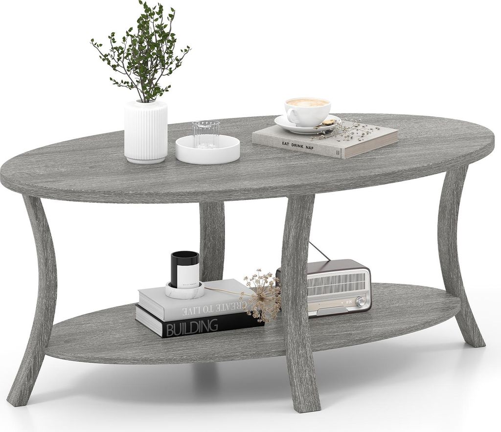 A gray oval coffee table with two shelves, decorated with a plant, books, a cup of coffee, and a vintage radio.