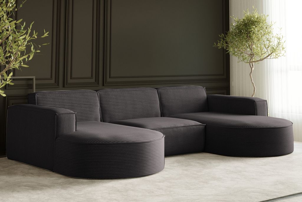A dark gray sectional sofa with a corduroy texture is shown in a modern living room setting, with a potted plant and decorative wall paneling.