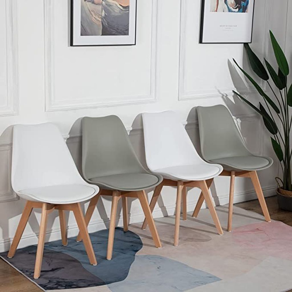 A row of four modern chairs with light wood legs against a white wall.