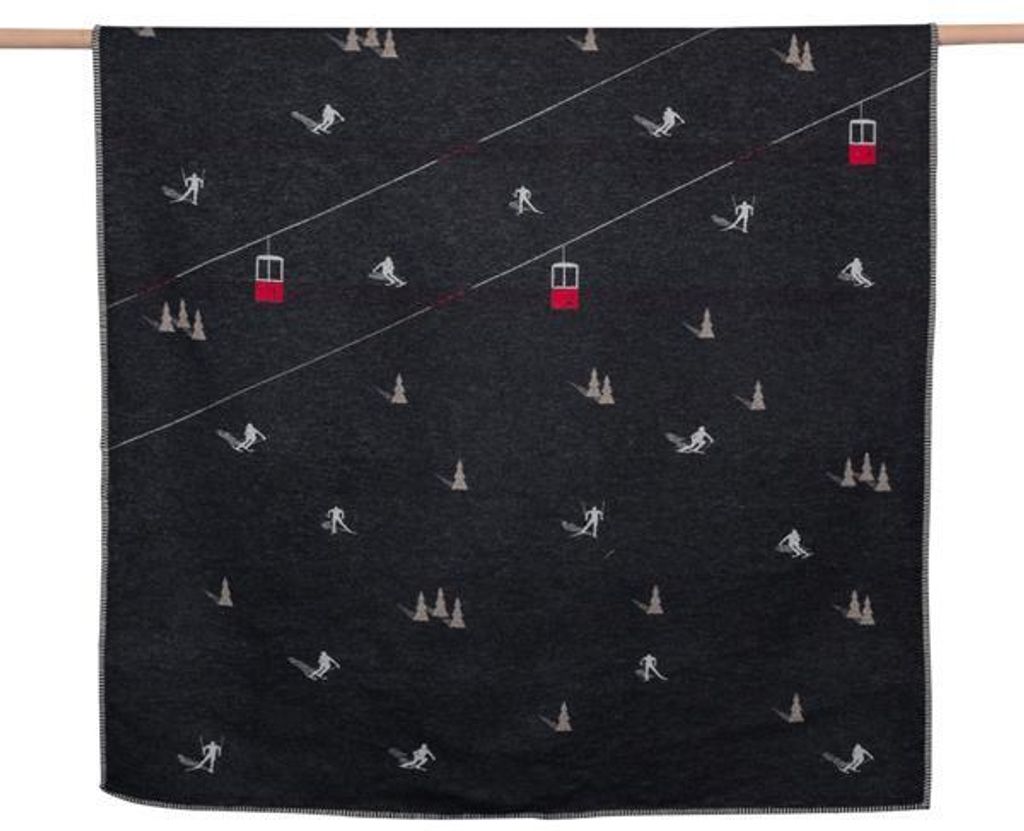 A dark blanket with a repeating pattern of skiers and ski lifts.