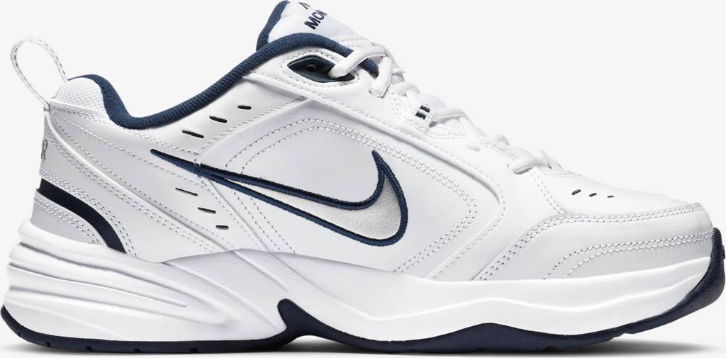 A white Nike Air Monarch IV sneaker with navy accents, shown from the side against a white background.