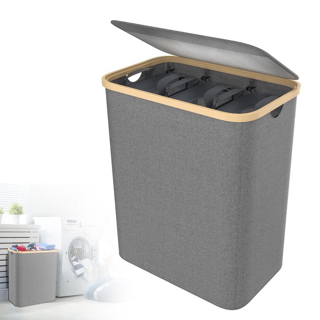 A grey laundry basket with a wooden rim and a partially open lid, shown against a white background. A smaller, similar laundry basket filled with clothes is visible in the lower-left corner, next to a washing machine.
