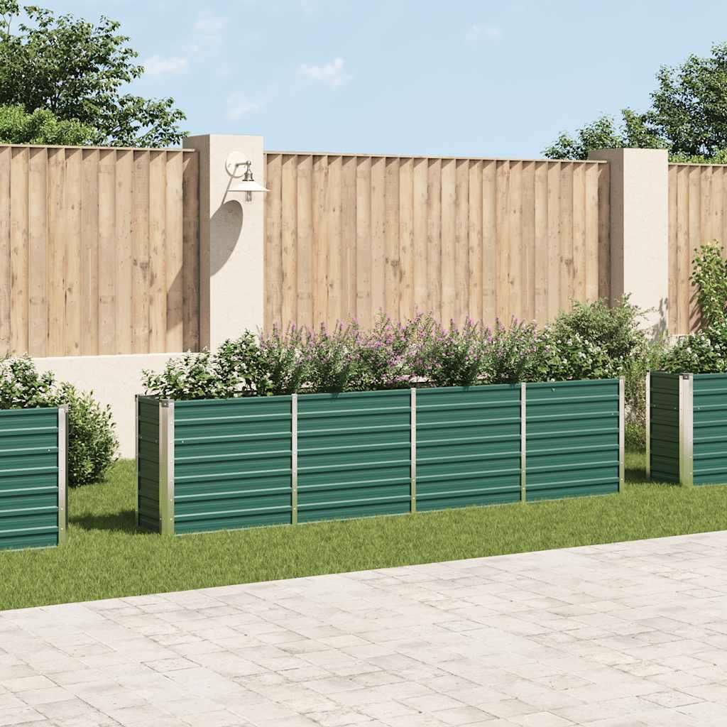 A row of green metal raised garden beds filled with plants, set against a wooden fence and a paved patio.