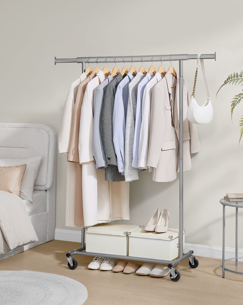 A clothing rack with clothes and shoes in a bedroom setting.