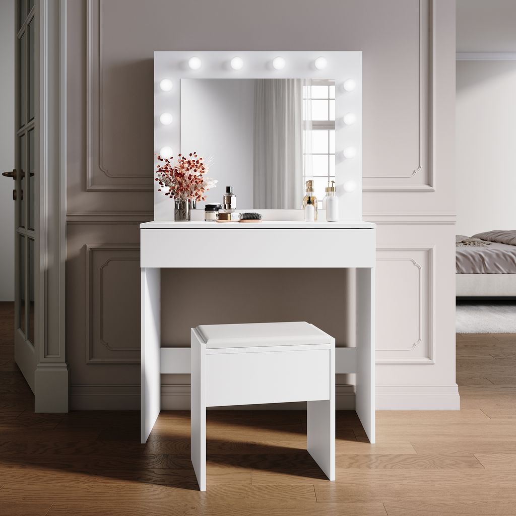 A white vanity table with a lighted mirror and a stool in a room.