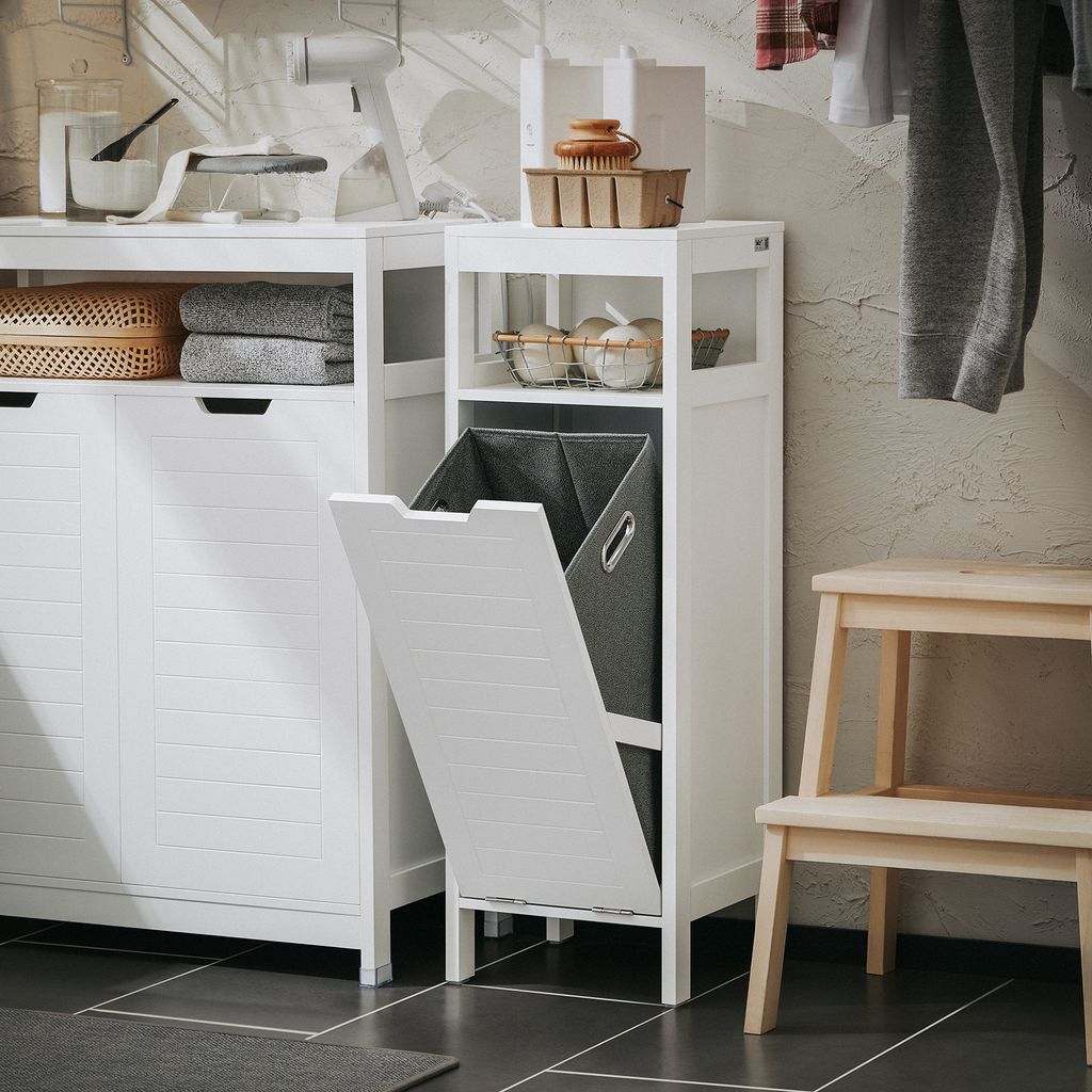 A laundry room scene with a white cabinet, a laundry sorter with a basket, and a wooden step stool.