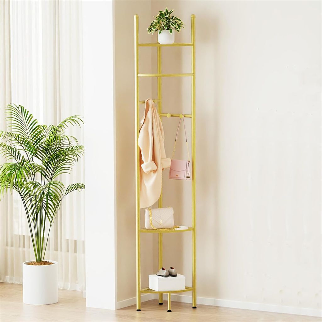 A gold metal corner shelf unit with clothes and bags on it, next to a large potted plant.