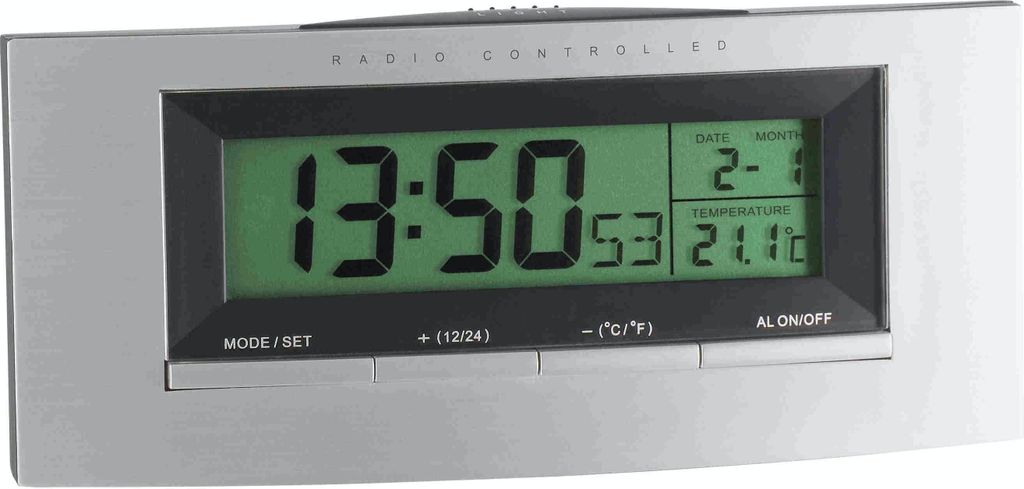 A digital alarm clock with a silver frame and a green LCD display showing the time, date, and temperature.