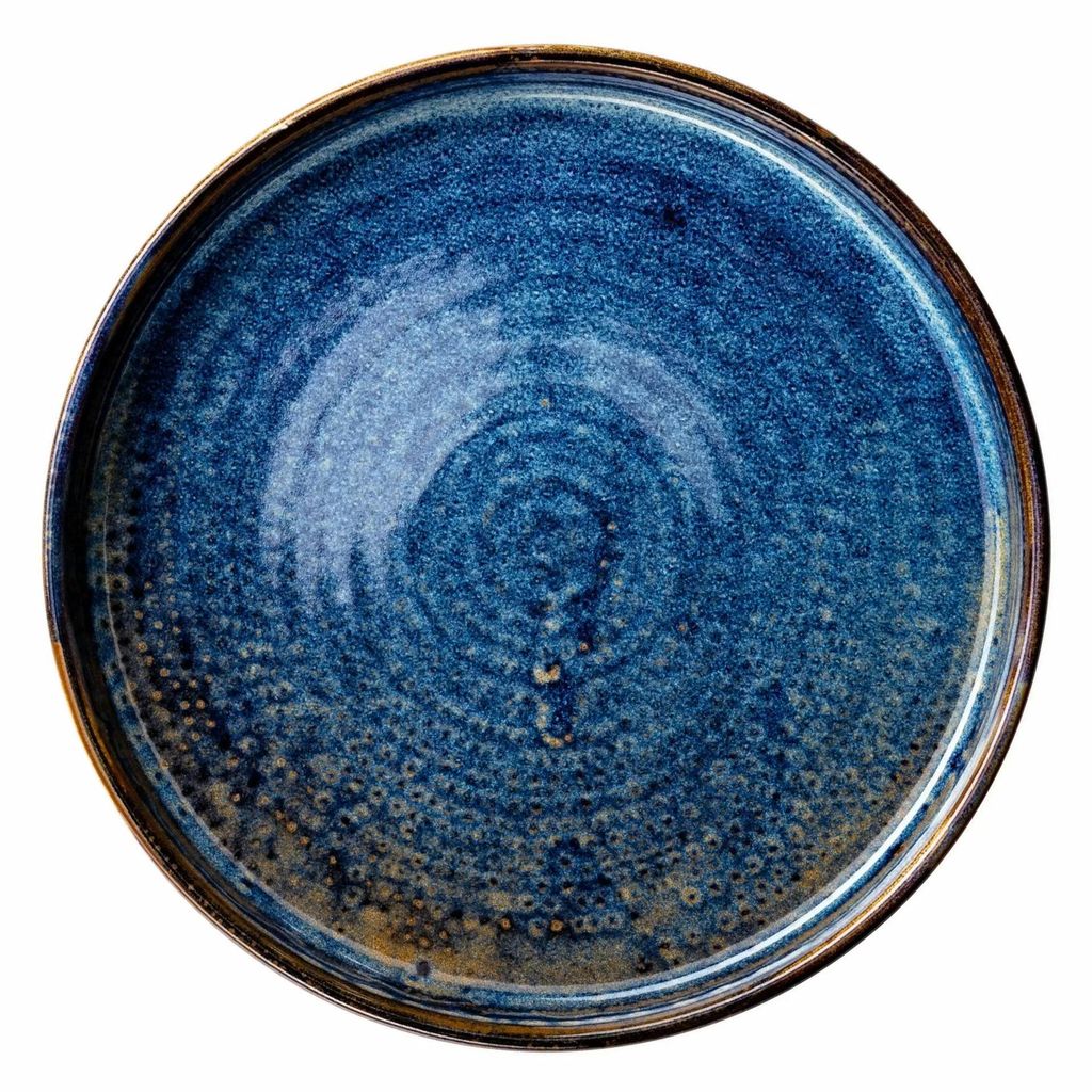 A top-down view of a single, flat, round plate with a dark blue speckled glaze and a brown rim.