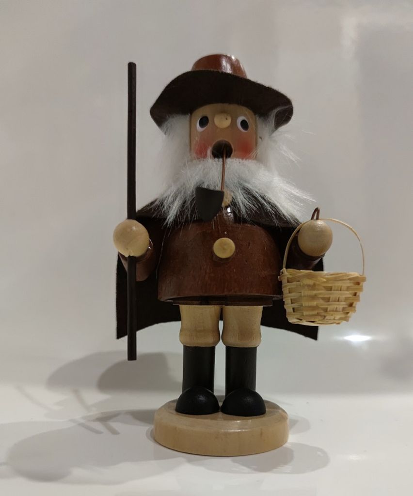 Ein Räuchermännchen Pilzsammler mit weißem Bart braunem Mantel und Hut Er trägt einen Korb mit Pilze