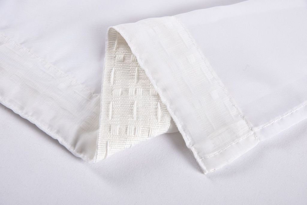 A close-up of white fabric, likely a curtain, folded to show texture and stitching.