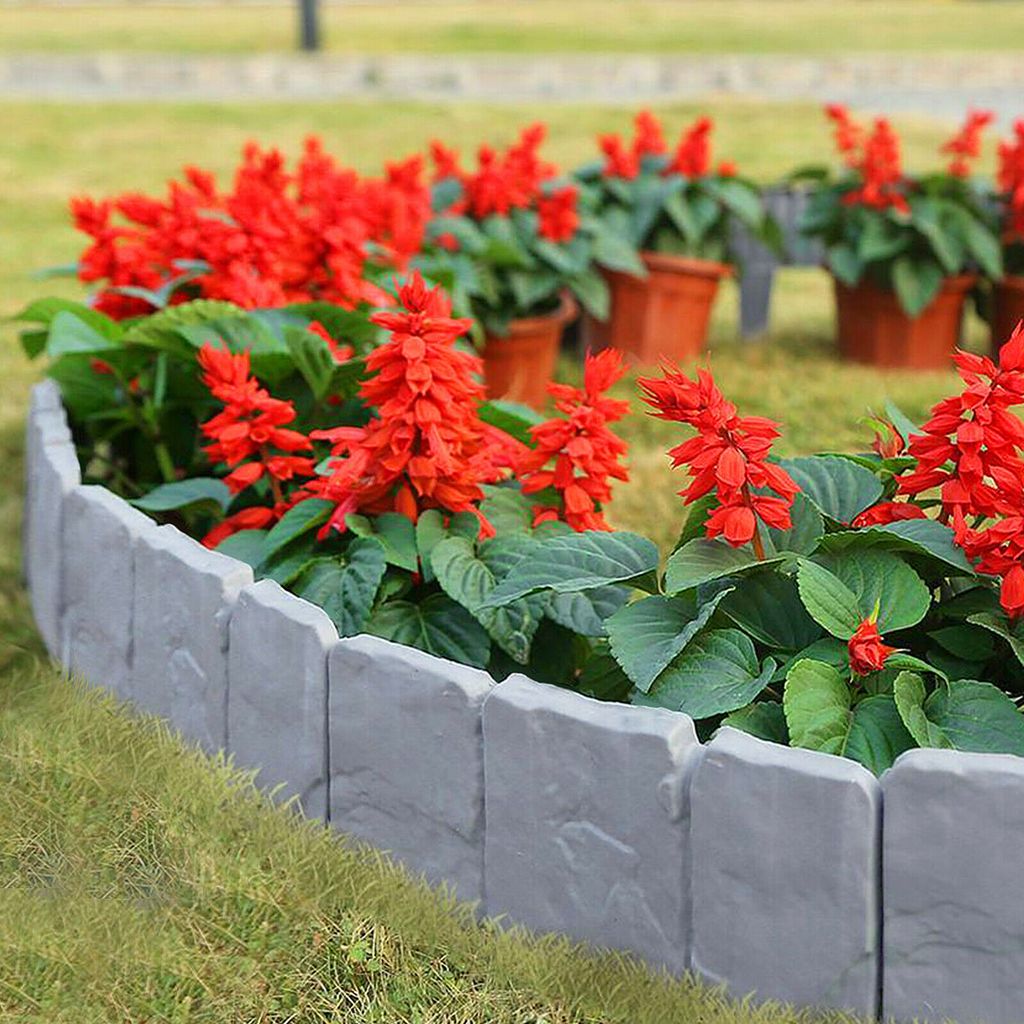A garden bed with red flowers bordered by gray stone-effect edging.