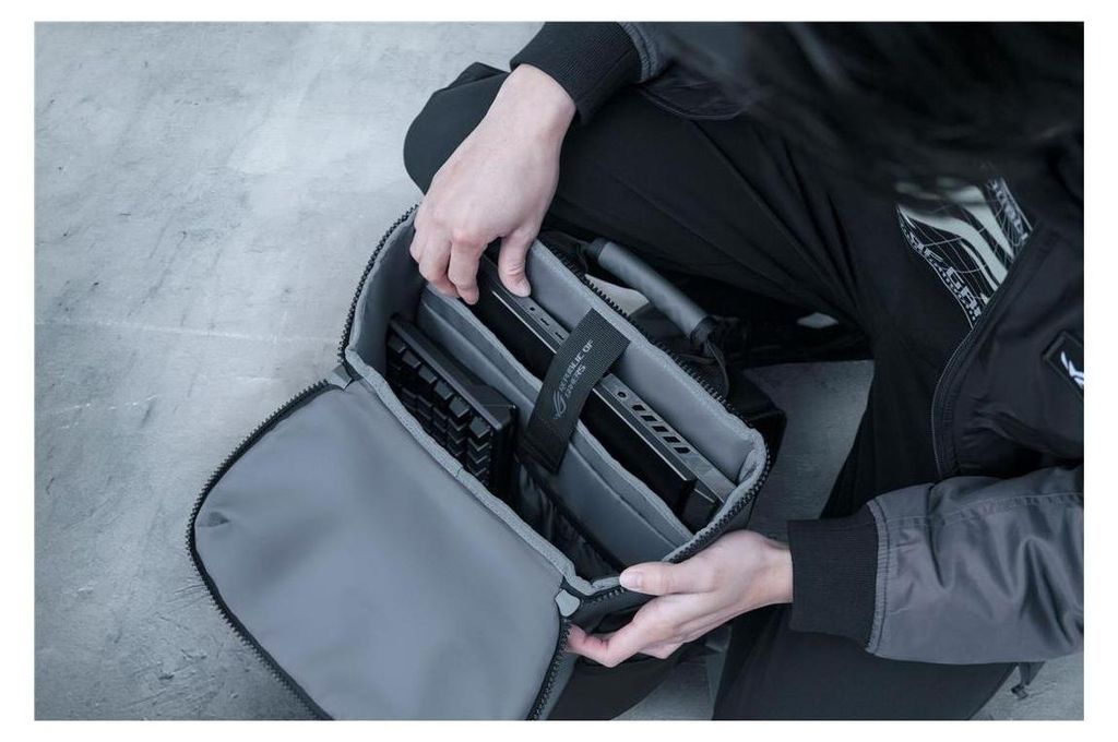 A person is packing a laptop into a backpack.