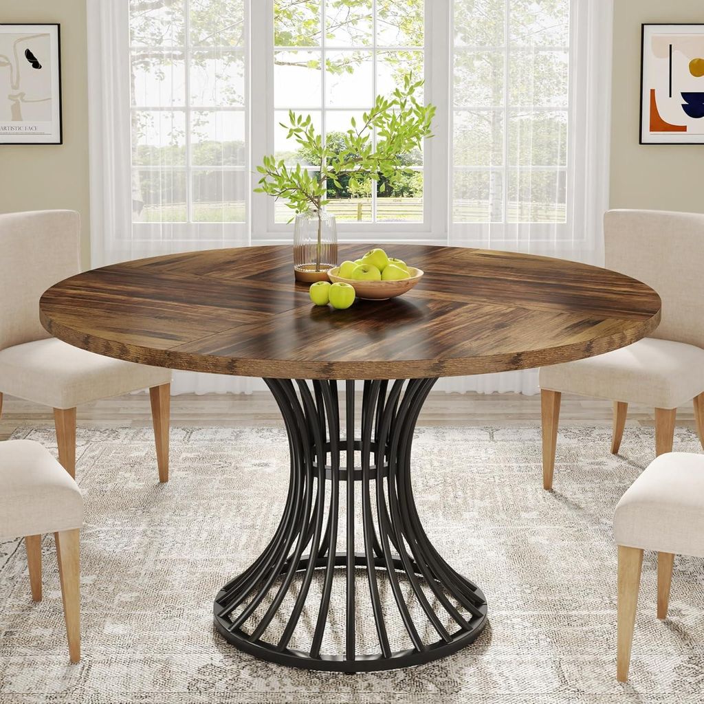 A round dining table with a wooden top and a black metal base, set in a dining room with chairs and a window in the background.