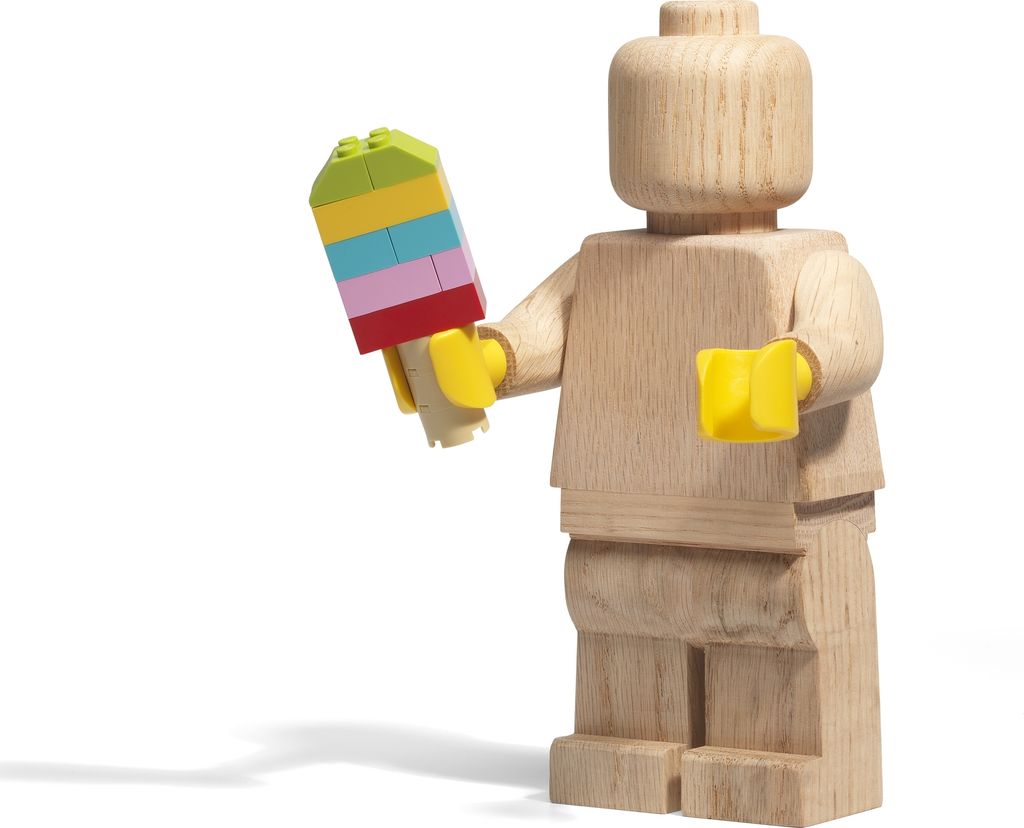 A wooden LEGO minifigure holding a colorful LEGO brick structure that resembles an ice cream or popsicle.