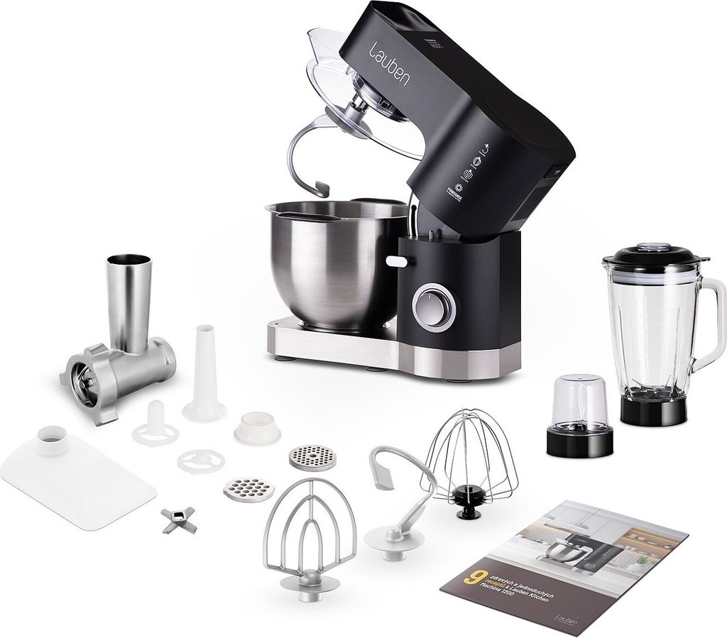 A black and silver kitchen machine with various attachments, a blender, and a booklet, displayed on a white background.