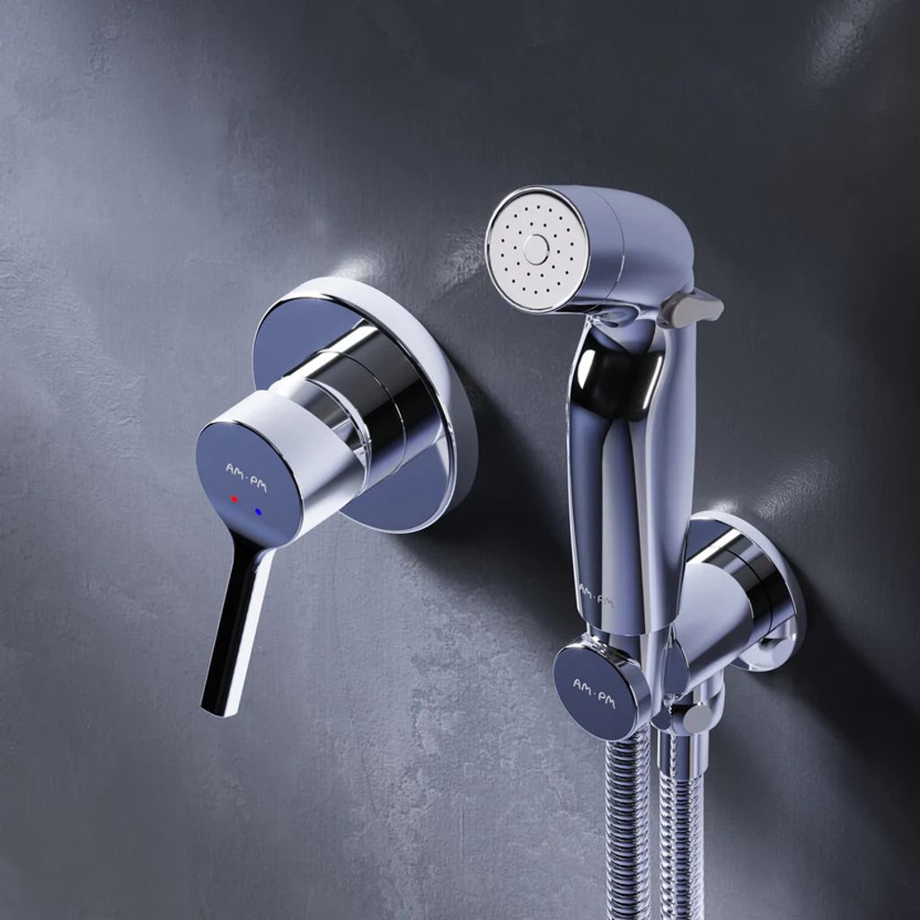 A chrome bidet faucet and hand sprayer are mounted on a textured gray wall.