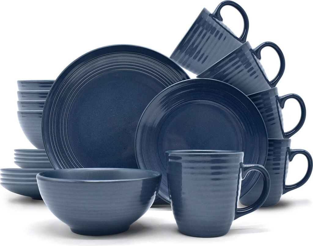 A collection of dark blue stoneware dishes and mugs are neatly stacked and arranged against a white background.